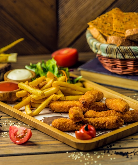 Palitos de pollo servidos con papas fritas, mayonesa y ketchup.