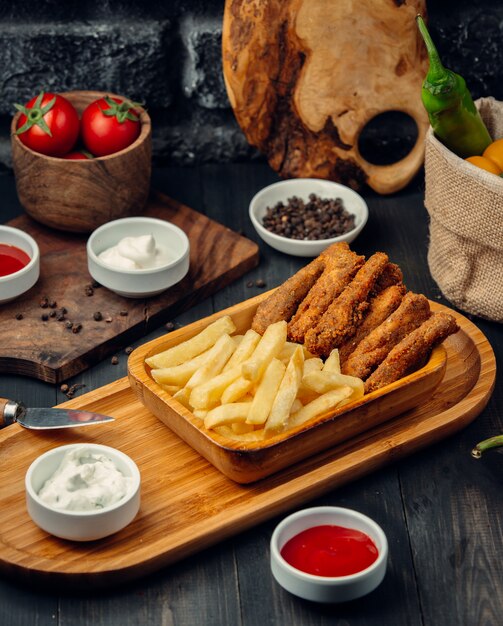 palitos de pollo servidos con papas fritas, mayonesa y salsa de tomate