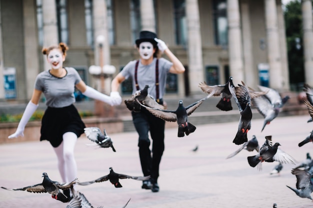 Palomas volando cerca de correr mimo pareja