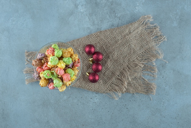 Palomitas de maíz confitadas apiladas en un soporte de vidrio junto a adornos navideños en la superficie de mármol