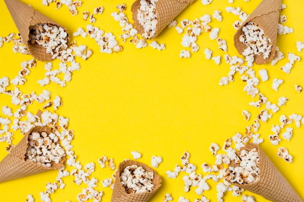 Foto gratuita palomitas de maíz con conos de galleta sobre fondo amarillo con espacio para escribir el texto