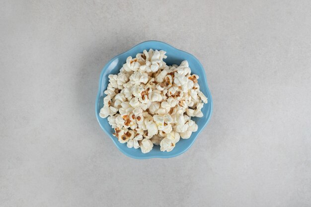 Palomitas de maíz crujientes en un pequeño cuenco azul sobre mármol.