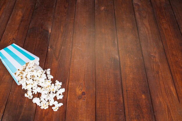 Palomitas de maíz derramado sobre la mesa de madera