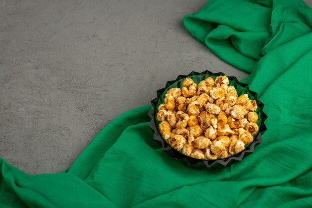 Palomitas de maíz dulce delicioso dentro de la placa verde sobre un pañuelo verde