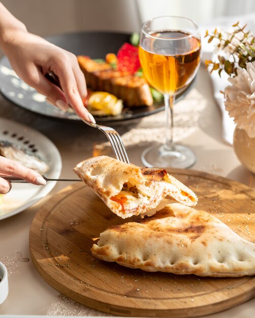 Pan aireado relleno de queso crema y carne sobre una plancha de madera