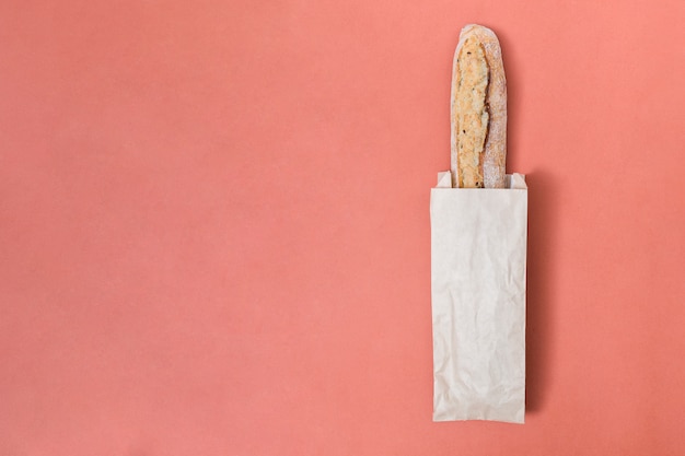 Pan de baguette en la bolsa de papel sobre el fondo de color