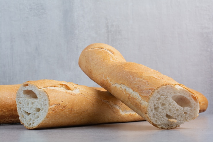 Foto gratuito pan baguette crujiente sobre superficie de mármol