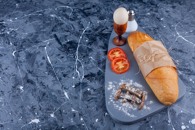 Pan baguette, verduras en rodajas, huevo cocido a bordo en azul.