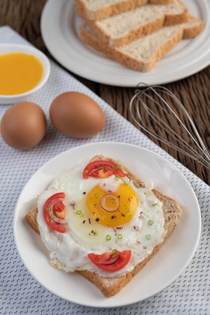 Pan colocado con un huevo frito con tomates, harina de tapioca y cebolletas en rodajas.
