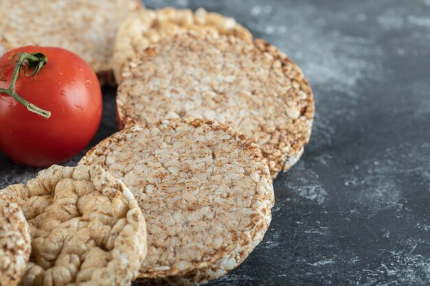 Pan crujiente inflado y tomate fresco sobre superficie de mármol