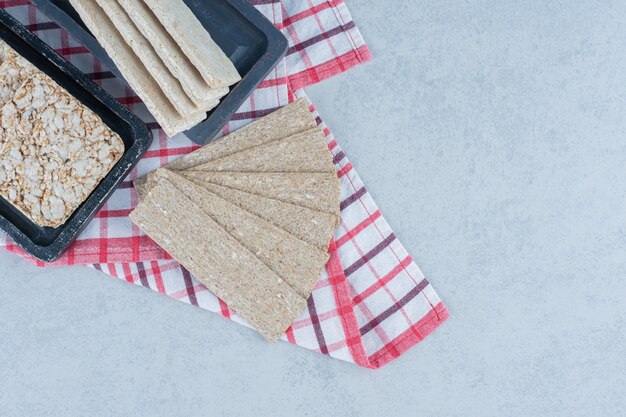 Foto gratuita pan crujiente y pastel de arroz inflado sobre toalla sobre mármol.