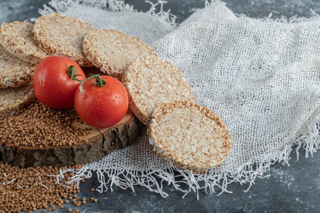 Pan crujiente, tomates y trigo sarraceno crudo sobre pieza de madera