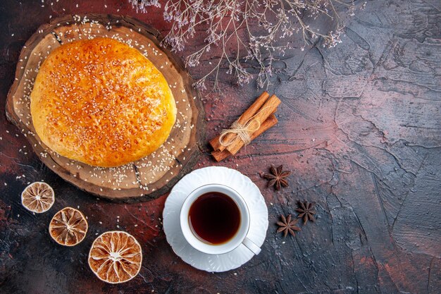 Pan dulce horneado de vista superior con taza de té en la superficie oscura