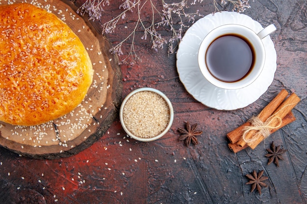 Pan dulce horneado de vista superior con taza de té en la superficie oscura