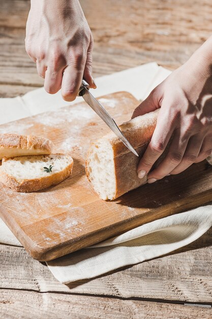 Pan de grano entero puesto en placa de madera de cocina con un chef con cuchillo de oro para cortar.