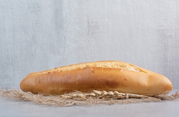 Pan de hogaza sobre arpillera con trigo. Foto de alta calidad