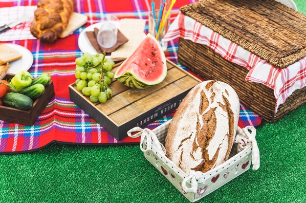 Pan horneado; Frutas y cesta de picnic en el césped.