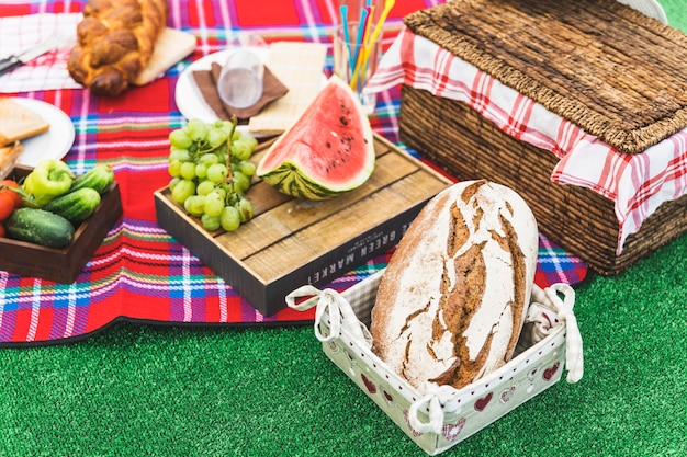 Pan horneado; Frutas y cesta de picnic en el césped.