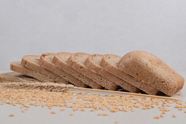 Pan integral fresco en rodajas con granos de avena sobre fondo blanco. Foto de alta calidad