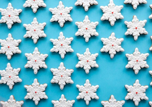 Foto gratuita pan de jengibre en forma de copos de nieve sobre un fondo azul.
