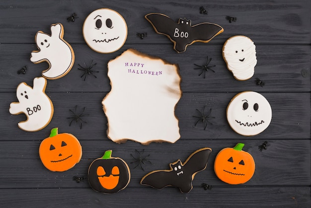 Foto gratuita pan de jengibre de halloween y arañas decorativas alrededor de papel ardiendo