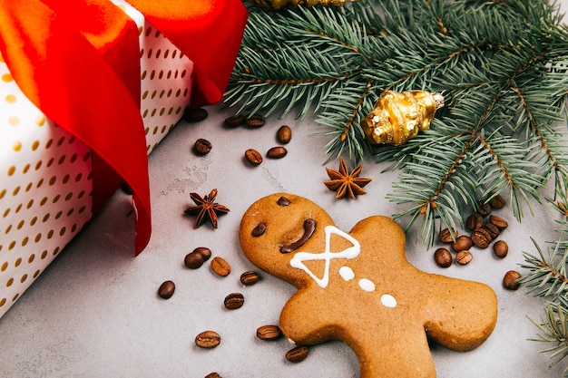 Pan de jengibre de Navidad, granos de café, rama de abeto y caja presente en piso gris