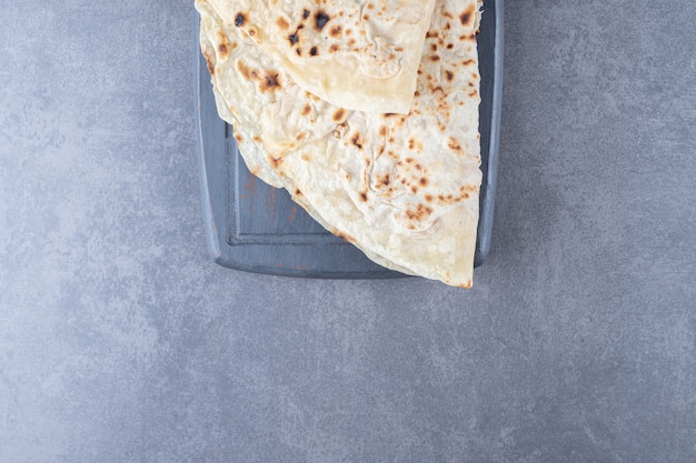 Pan lavash de trigo tradicional en la bandeja de madera sobre mesa de mármol.