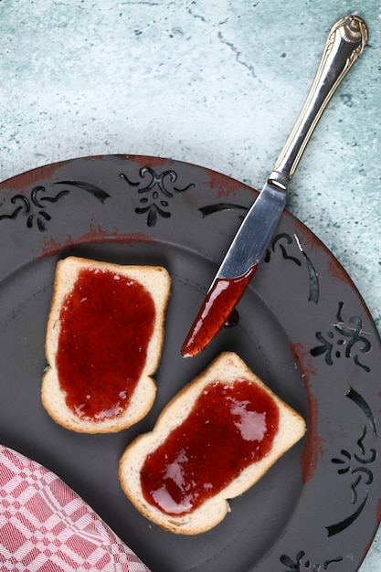 Foto gratuita pan con mermelada de fresa en placa gris.