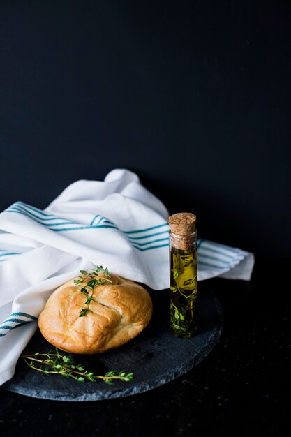 Pan de pan tomillos Aceite de oliva y servilleta blanca en pizarra sobre fondo negro