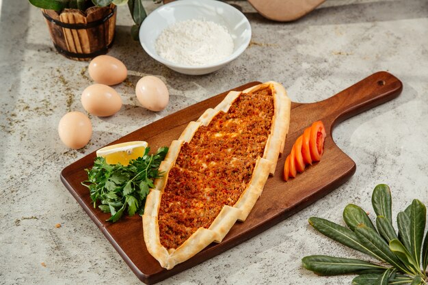 pan plano de pide turco con carne picada y cobertura de tomate