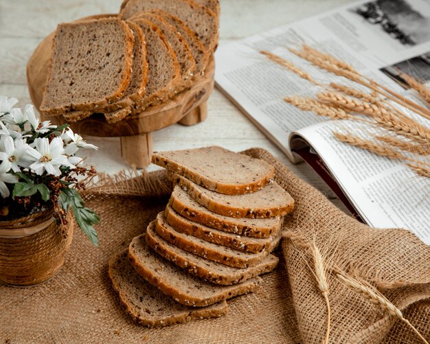 Pan rebanado con rama de trigo y flores