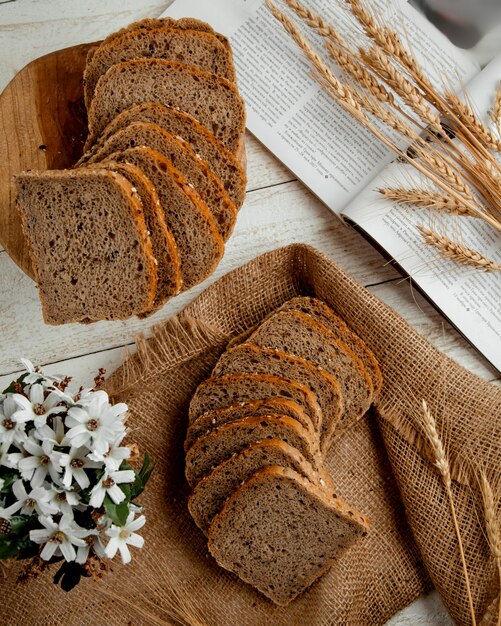 Pan rebanado con rama de trigo y flores