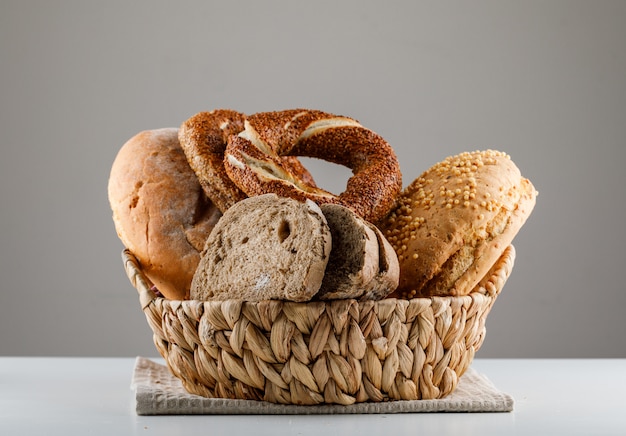 Pan rebanado con vista lateral de bagel turco sobre una superficie blanca y gris