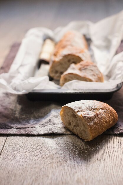 Pan recién horneado a la mitad espolvoreado con harina en una mesa de madera