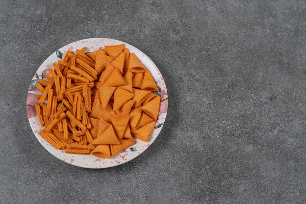 Pan seco con sabor a queso chips de maíz en forma de cono en placa sobre la superficie de mármol