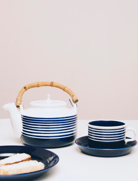 Un pan; tetera y taza de café en el escritorio contra el fondo coloreado