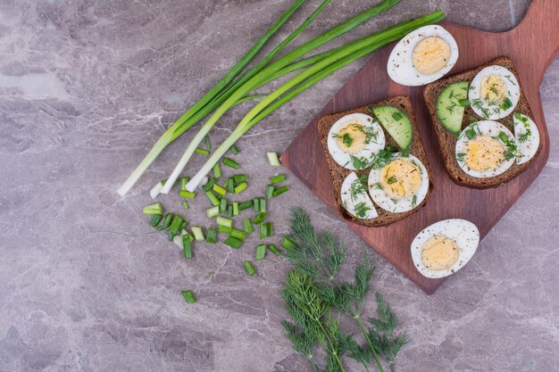 Pan tostado con huevos duros y hierbas servido con una taza de té.