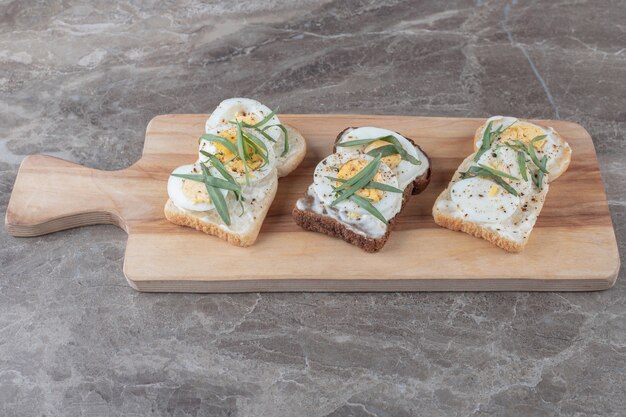 Pan tostado con huevos duros sobre tabla de madera.