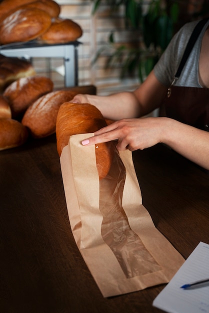 Foto gratuita panadero femenino con pan horneado en la pastelería