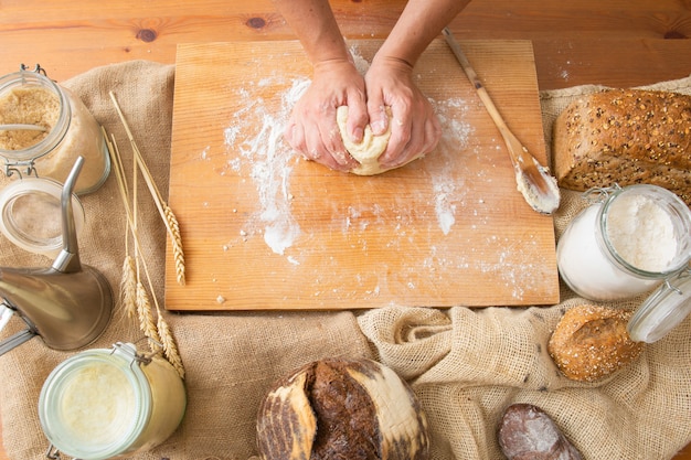 Panadero formando masa para pastelería sobre tabla de madera
