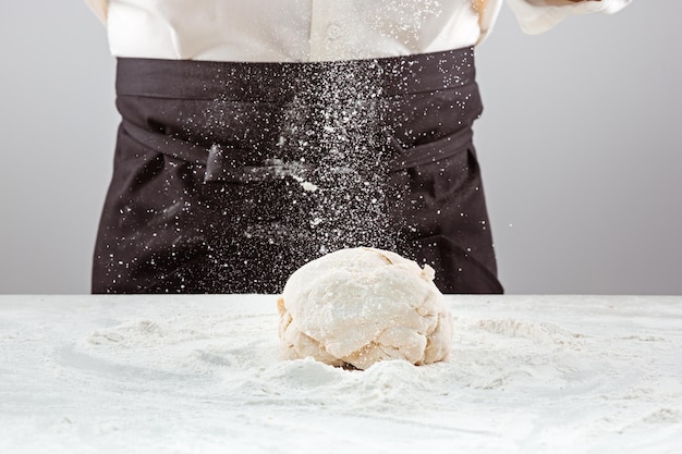 El panadero haciendo pan, manos masculinas, amasando una masa, cocinando abrigo