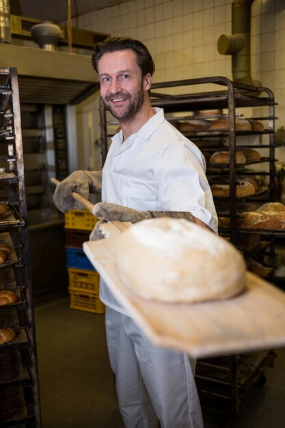 Panadero que sostiene el pan cocido en una cuchara de madera