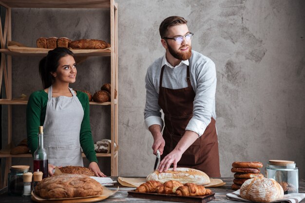 Panaderos de pareja amorosa alegre mirando a un lado.