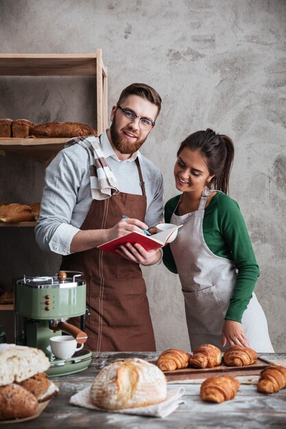 Panaderos de pareja amorosa feliz de pie cerca de pan.