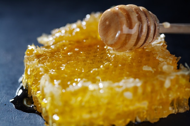 Panales con miel fresca y cuchara de miel sobre fondo oscuro. De cerca