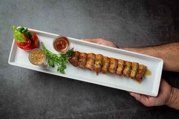 Panceta de cerdo frita con salsa de pescado sobre fondo oscuro