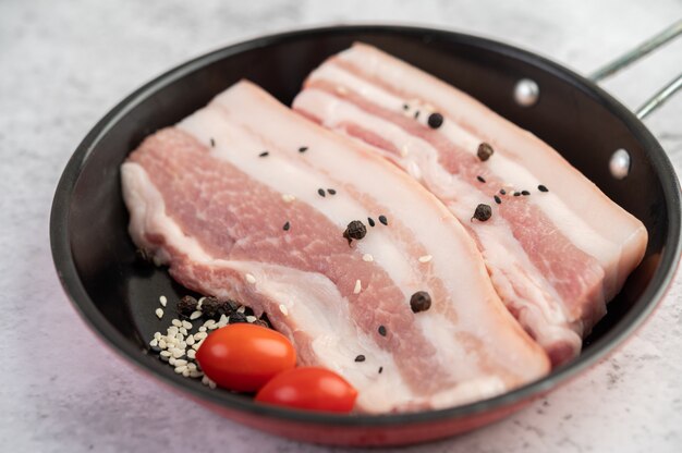 Panceta de cerdo en una sartén con semillas de pimiento Tomates y especias