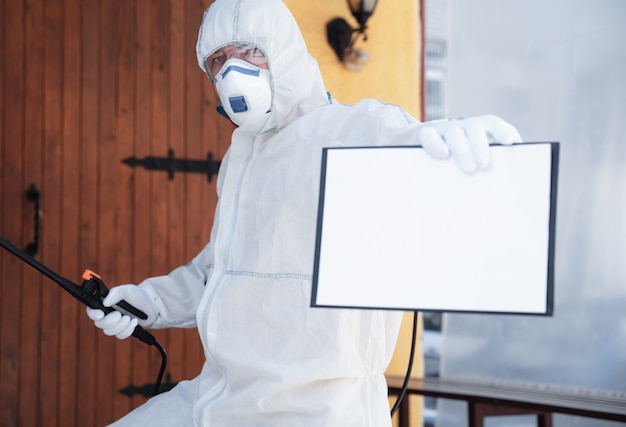 Foto gratuita pandemia de coronavirus. desinfectante en un traje protector y mascarilla rocía desinfectantes en la casa u oficina