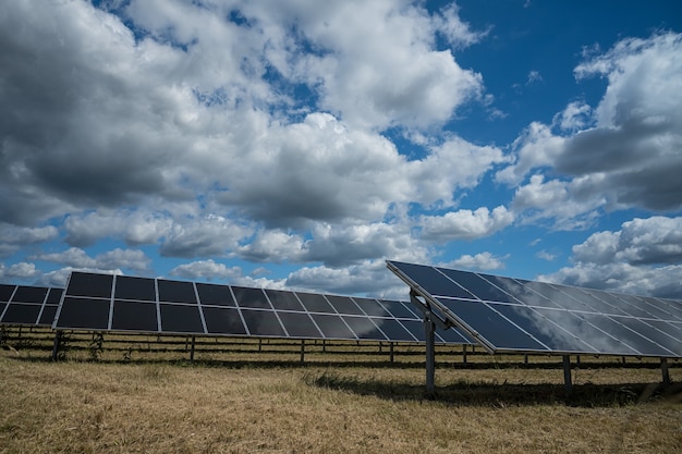 Paneles solares utilizados para energía renovable en el campo bajo el cielo lleno de nubes.