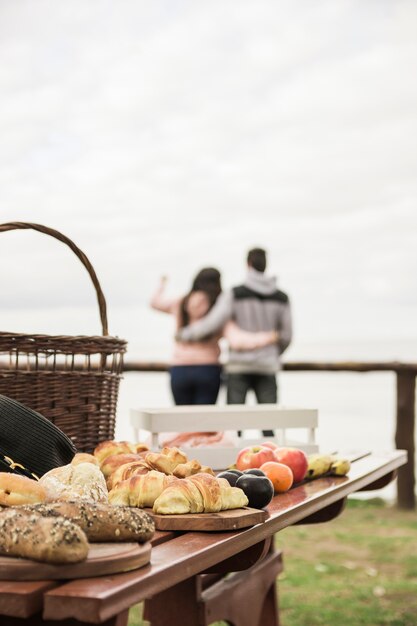 Panes y frutas al horno en mesa de madera y pareja en el fondo